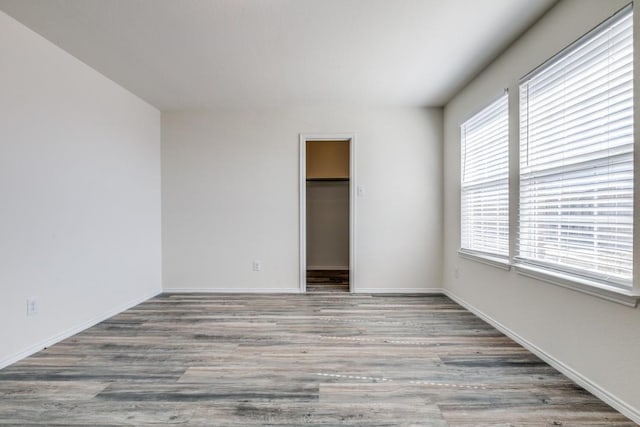 2305 Simmental Rd, Fort Worth, TX 76131 - unfurnished bedroom featuring wood finished floors, a walk in closet, baseboards, and a closet