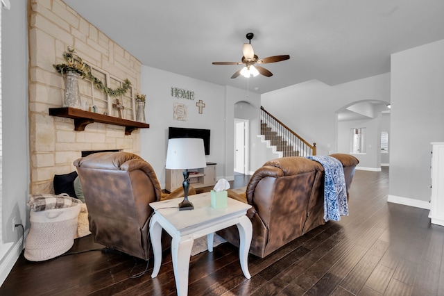 living room featuring arched walkways, stairway, dark wood-style floors, and a ceiling fan