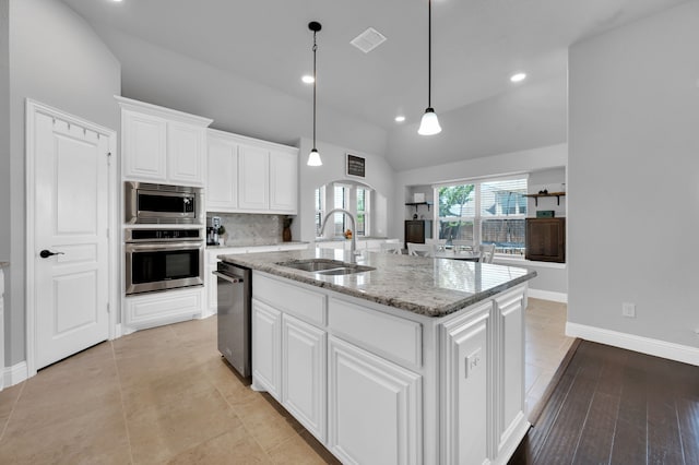 kitchen featuring a sink, white cabinets, vaulted ceiling, appliances with stainless steel finishes, and decorative backsplash