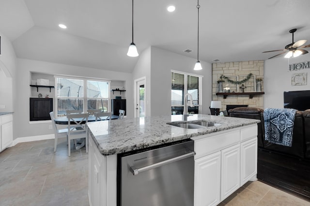 kitchen with light stone counters, open floor plan, a stone fireplace, stainless steel dishwasher, and a sink