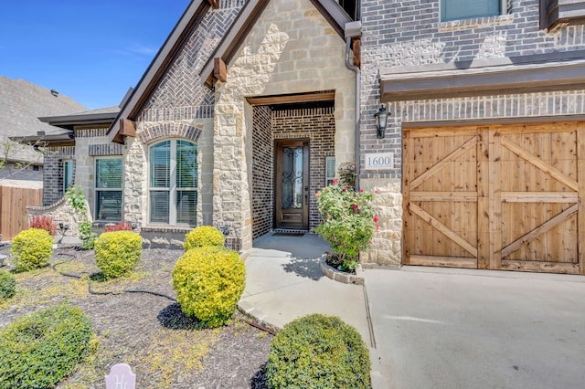 property entrance with a garage, stone siding, and brick siding