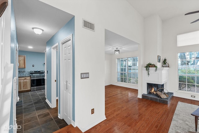 corridor with dark wood-style floors, visible vents, and baseboards