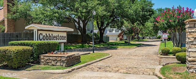 view of community featuring fence and decorative driveway