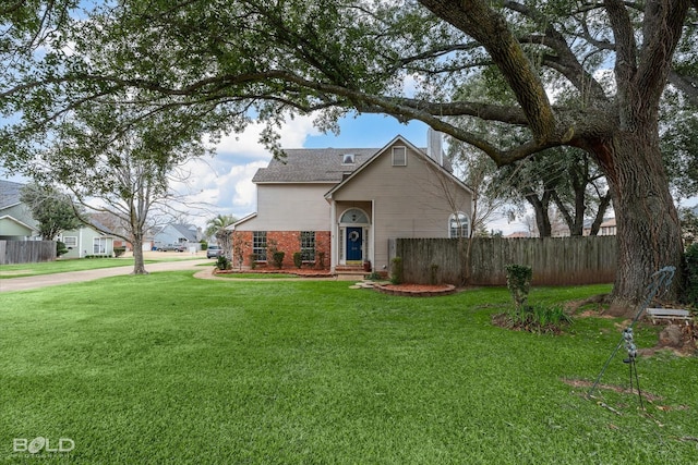 view of front facade with brick siding, a front lawn, and fence