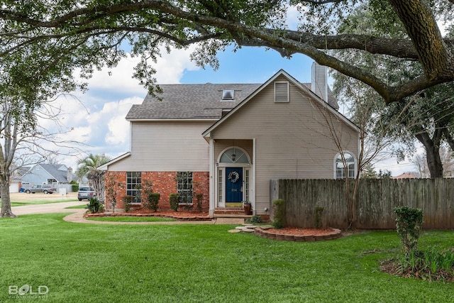 traditional home featuring a shingled roof, a chimney, fence, a front yard, and brick siding