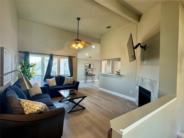 living area with light wood-type flooring, visible vents, a fireplace, and baseboards