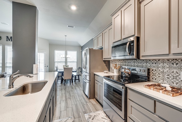 kitchen featuring gray cabinetry, stainless steel appliances, a sink, visible vents, and backsplash