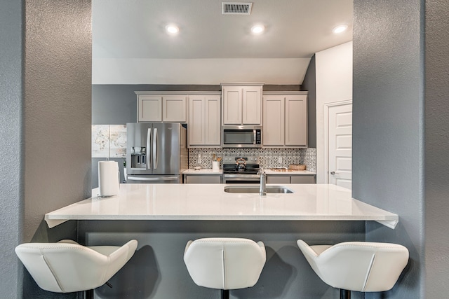 kitchen with tasteful backsplash, a kitchen bar, visible vents, and stainless steel appliances