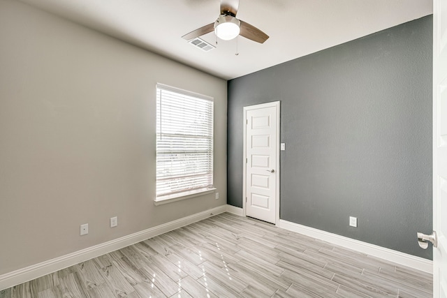 empty room featuring baseboards, visible vents, light wood-style flooring, and a ceiling fan