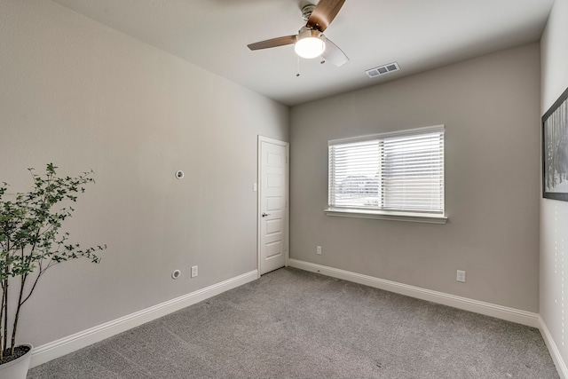 carpeted spare room with visible vents, ceiling fan, and baseboards