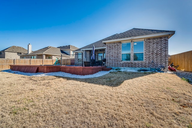 back of property featuring a yard, a fenced backyard, and brick siding