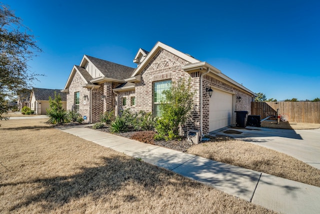 view of front of property featuring a garage, brick siding, fence, and driveway