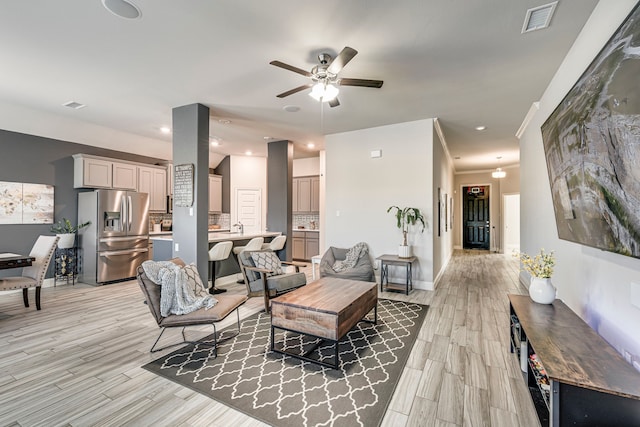 living room with light wood finished floors, visible vents, and baseboards