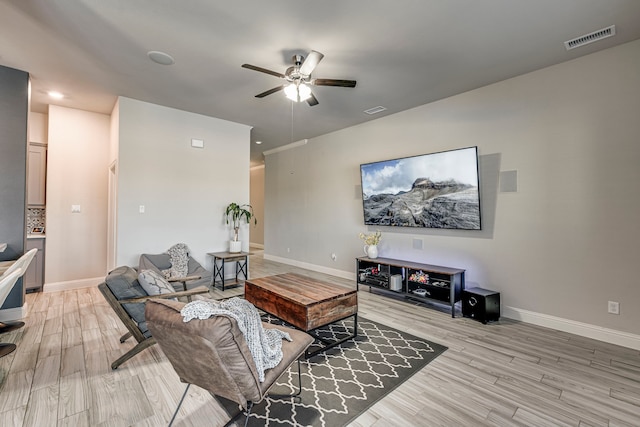 living area with light wood-type flooring, visible vents, ceiling fan, and baseboards