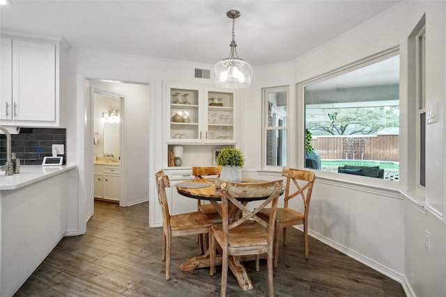 dining room with ornamental molding, visible vents, dark wood finished floors, and baseboards