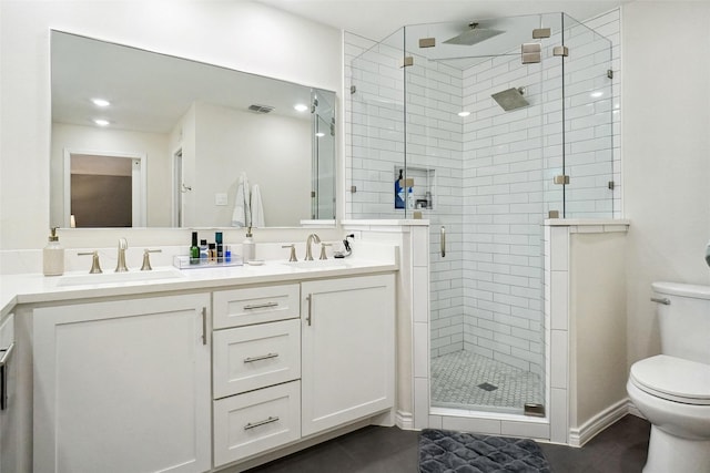 full bathroom with double vanity, a stall shower, a sink, and toilet