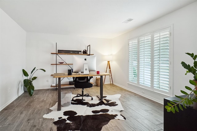 office space with wood finished floors, visible vents, and baseboards