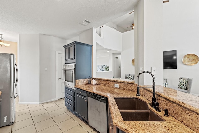 kitchen with visible vents, appliances with stainless steel finishes, light tile patterned flooring, a sink, and light stone countertops