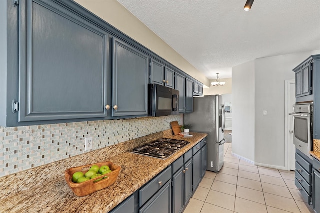 kitchen featuring light tile patterned floors, tasteful backsplash, stainless steel appliances, a textured ceiling, and a notable chandelier