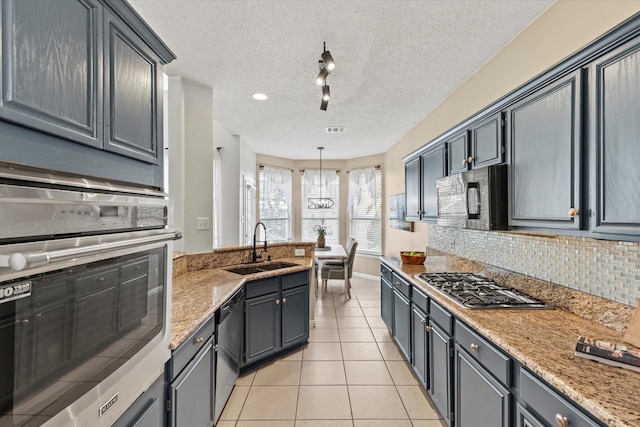 kitchen featuring light tile patterned floors, tasteful backsplash, stainless steel appliances, a textured ceiling, and a sink