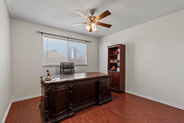 office featuring a textured ceiling, dark wood-style flooring, a ceiling fan, and baseboards