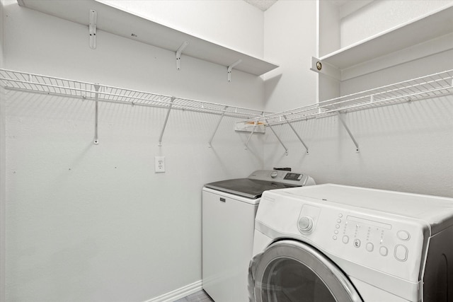 laundry area with laundry area, washing machine and dryer, and baseboards