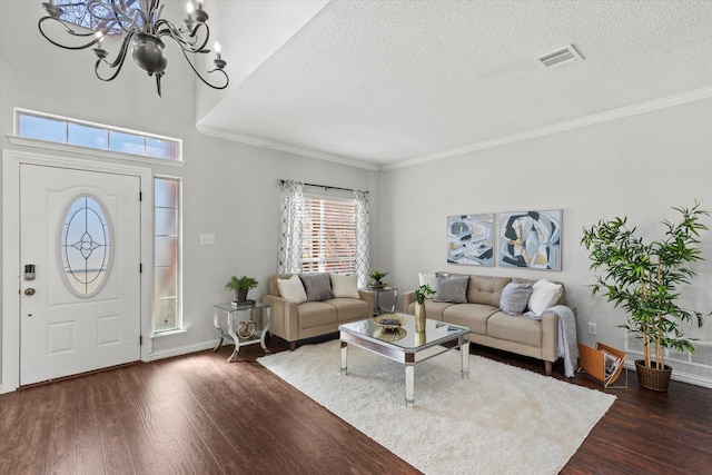 living room featuring a textured ceiling, hardwood / wood-style flooring, a notable chandelier, visible vents, and ornamental molding