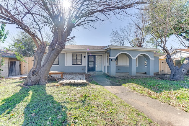 view of front facade with a porch, a front yard, fence, and stucco siding