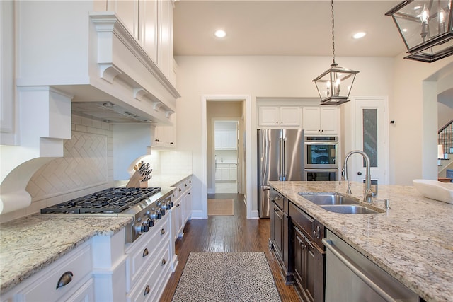 kitchen with dark wood-style flooring, custom exhaust hood, appliances with stainless steel finishes, white cabinetry, and a sink