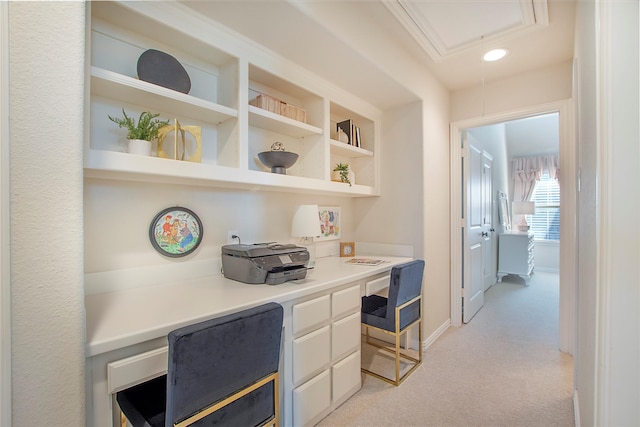 home office featuring light carpet, attic access, baseboards, and built in study area