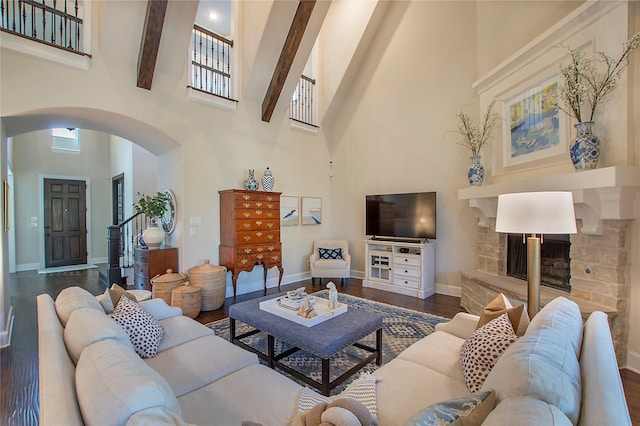 living room featuring arched walkways, a high ceiling, dark wood finished floors, and baseboards