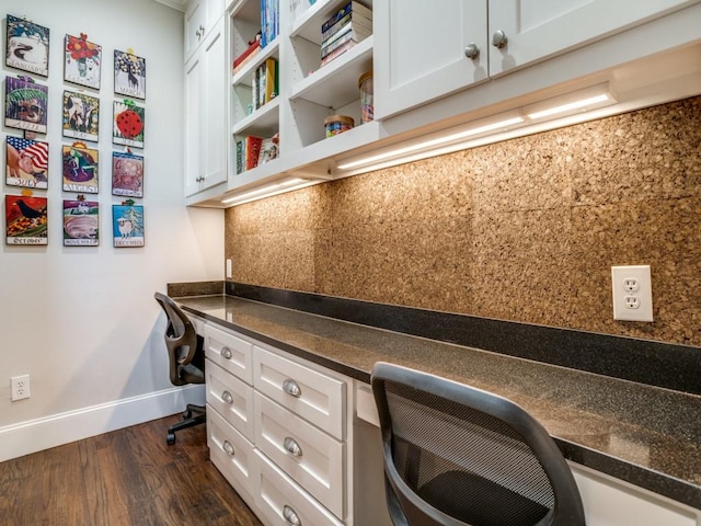 office space featuring dark wood-type flooring, built in desk, and baseboards