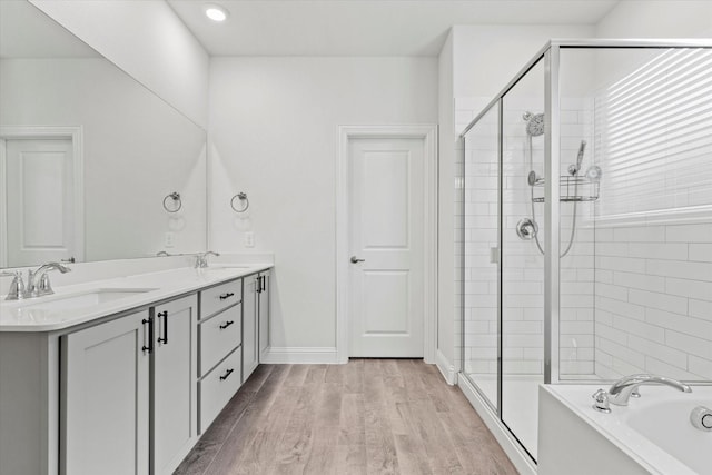 bathroom with wood finished floors, a stall shower, a sink, and a bath