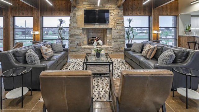 living room with a stone fireplace, wood walls, and beam ceiling