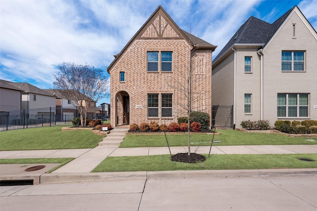 view of front facade with a front yard, a gate, brick siding, and fence