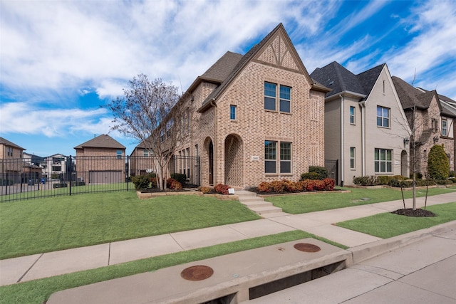tudor-style house featuring fence, brick siding, and a front yard