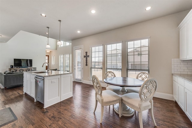 kitchen featuring dark wood-style flooring, decorative backsplash, open floor plan, white cabinets, and a sink