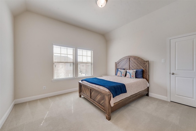 bedroom with lofted ceiling, light colored carpet, and baseboards