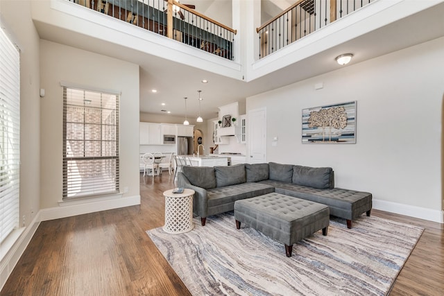 living area featuring a high ceiling, recessed lighting, wood finished floors, and baseboards