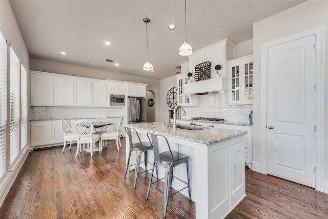 kitchen featuring a breakfast bar, stainless steel appliances, dark wood-type flooring, white cabinets, and a sink