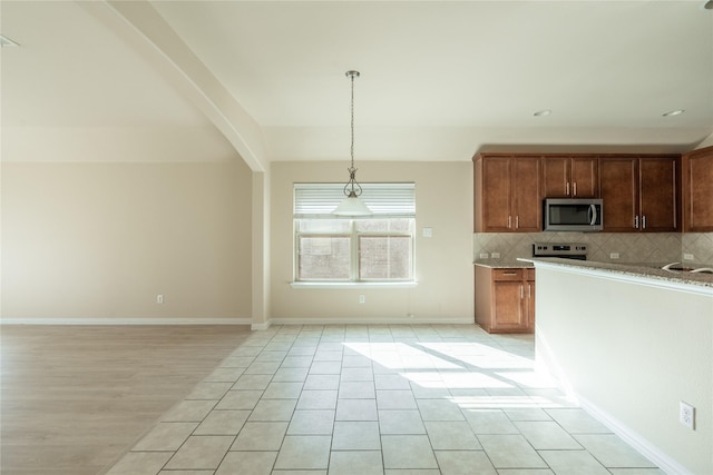 kitchen with stainless steel appliances, baseboards, light countertops, decorative backsplash, and decorative light fixtures