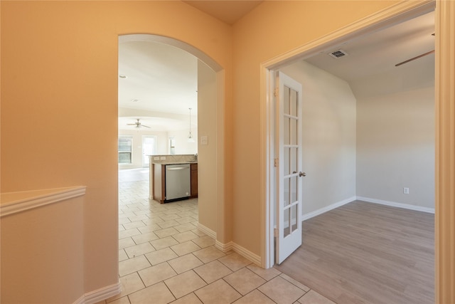 hallway with arched walkways, light tile patterned floors, visible vents, and baseboards