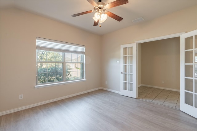 unfurnished room with baseboards, visible vents, ceiling fan, wood finished floors, and french doors