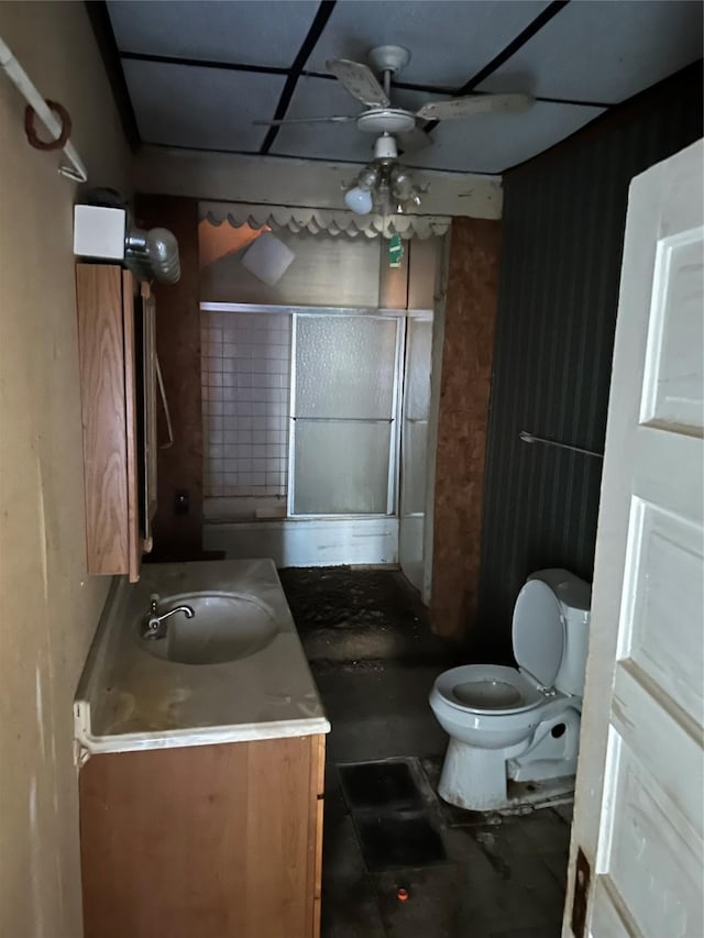 bathroom featuring a shower with shower door, ceiling fan, vanity, and toilet