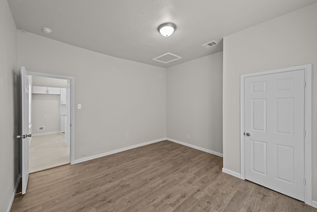 spare room featuring baseboards, visible vents, and wood finished floors