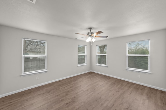 empty room featuring ceiling fan, baseboards, and wood finished floors