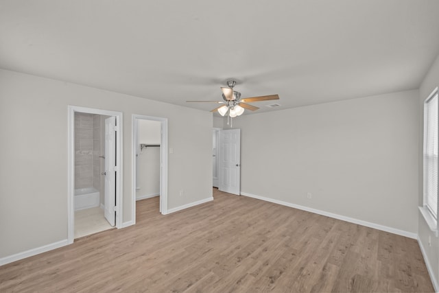 unfurnished bedroom featuring light wood-type flooring, a spacious closet, baseboards, and a closet