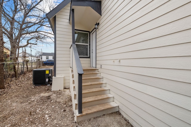 view of exterior entry with fence and central air condition unit