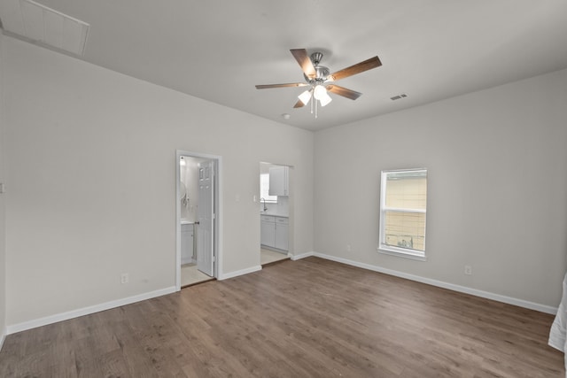 unfurnished bedroom featuring baseboards, visible vents, ensuite bathroom, and wood finished floors