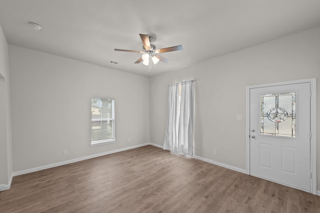 interior space featuring baseboards, visible vents, a ceiling fan, and wood finished floors